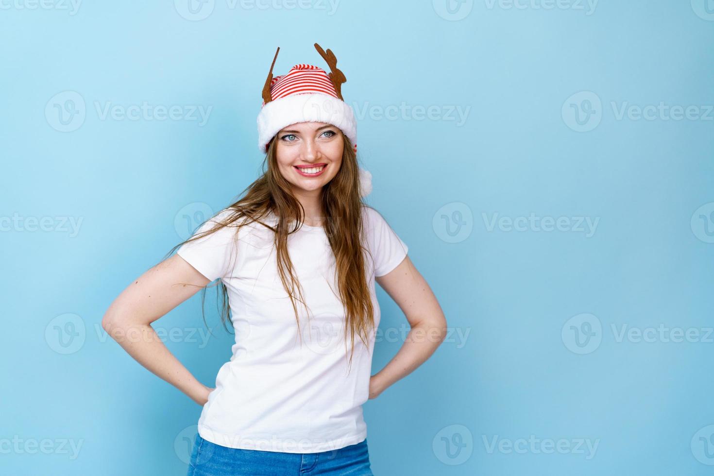 Girl with gift in hand and deer horns on blue background smiles with joy photo