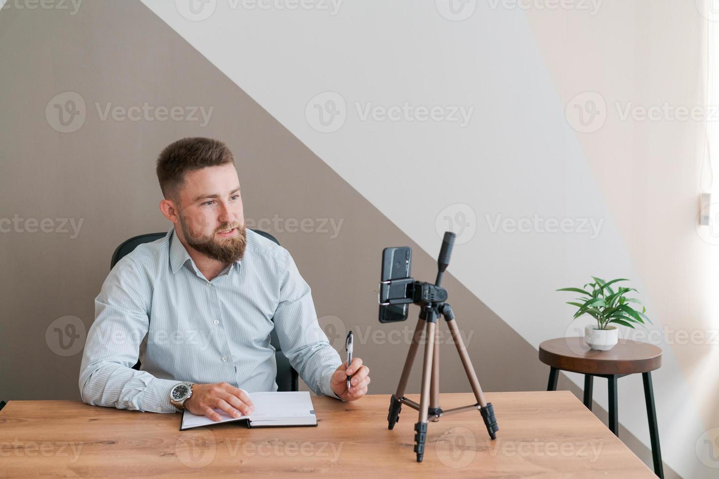 Young bearded businessman working in office sitting at table using smartphone photo
