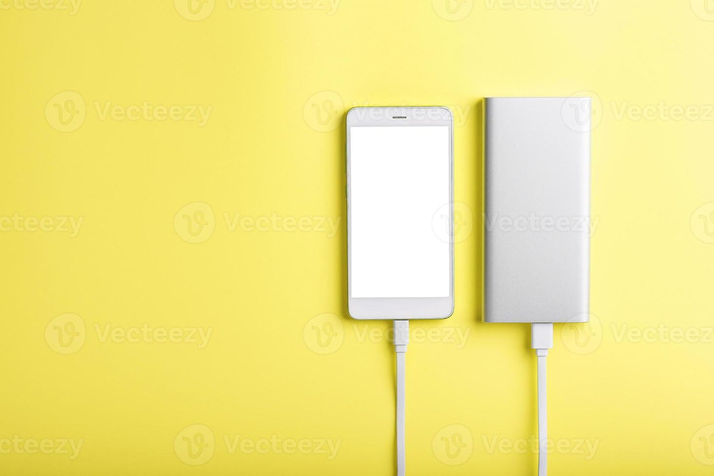 Smartphone and power bank on a yellow background isolate. photo