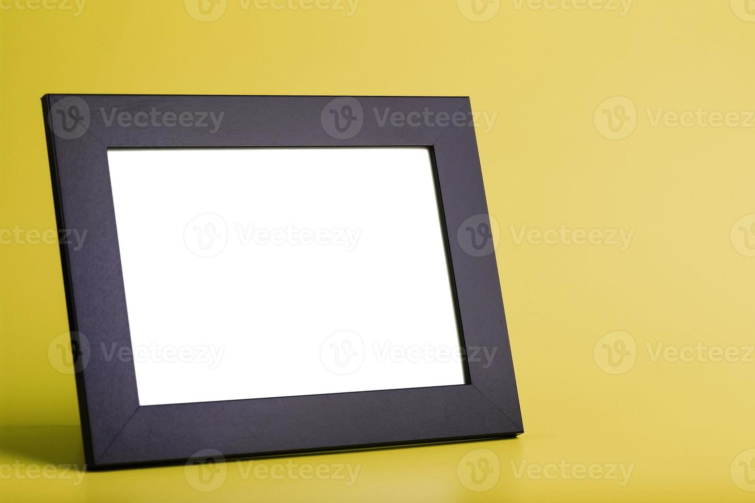 Black photo frame with free space on a yellow background.