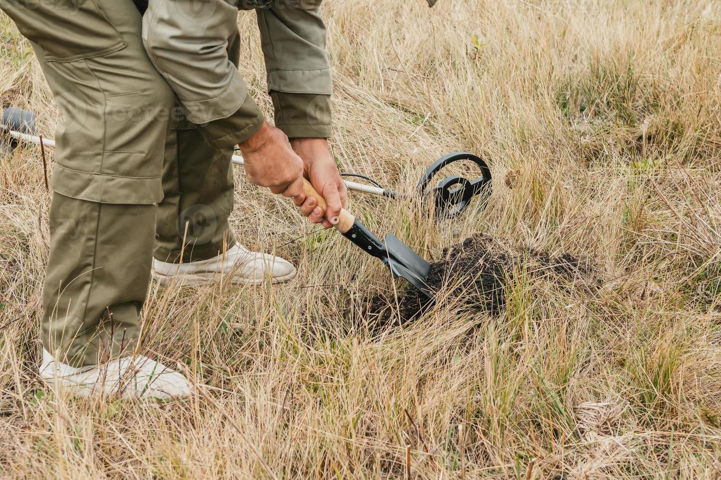 Man with electronic metal detector device working on outdoors. photo