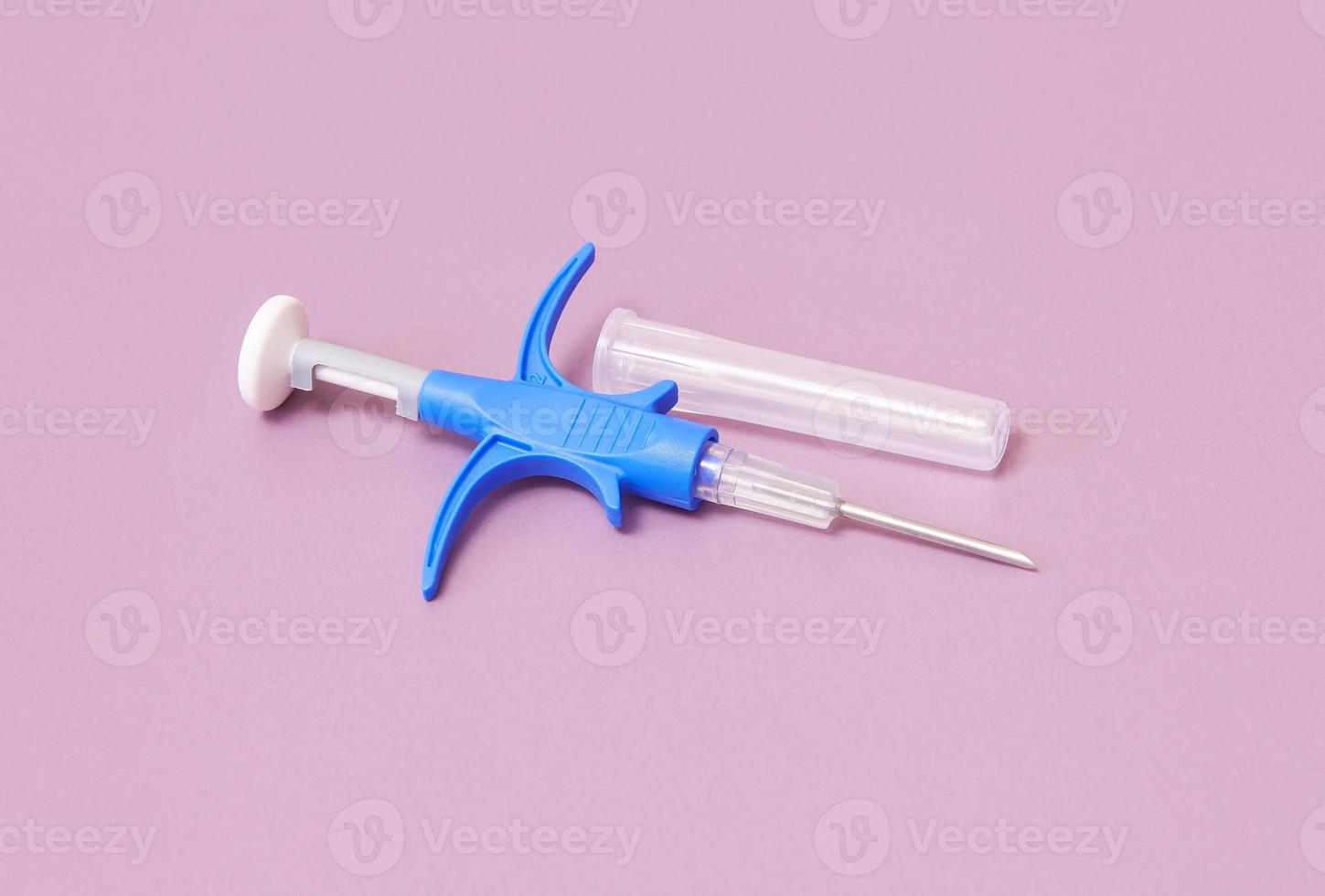 a syringe with a microchip for identifying animals on a pink background, close-up photo