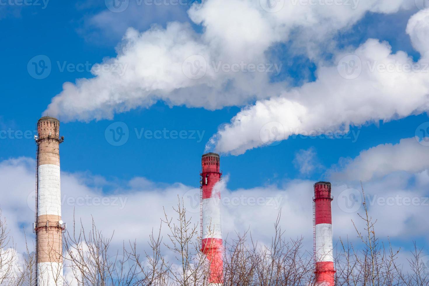 Close-up of the pipes of a thermal power plant with white steam in winter. The concept of environmental pollution and emissions of harmful substances into the atmosphere. photo