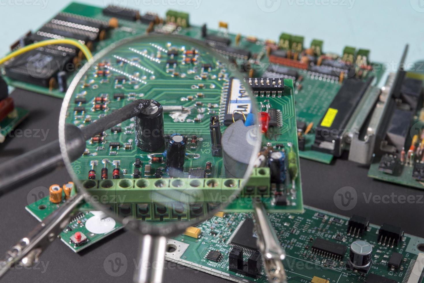 A glass magnifier with a focus on electronic waste printed circuit Board. photo