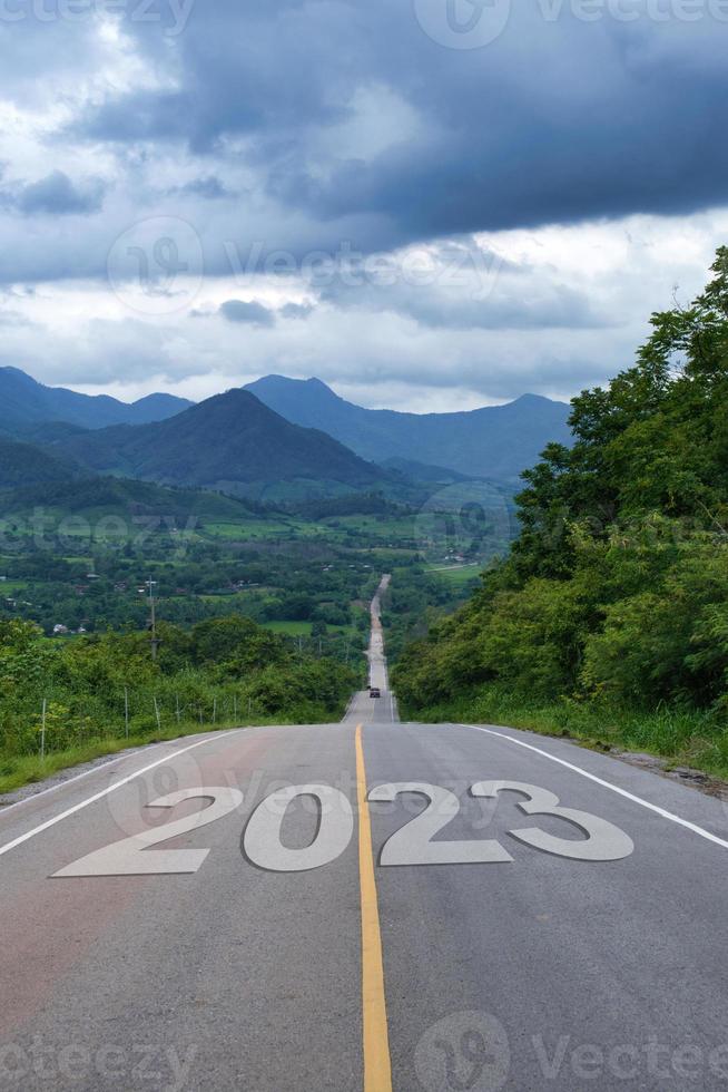 Country road leading to mountains numbered 2023. 2023 start concept. photo