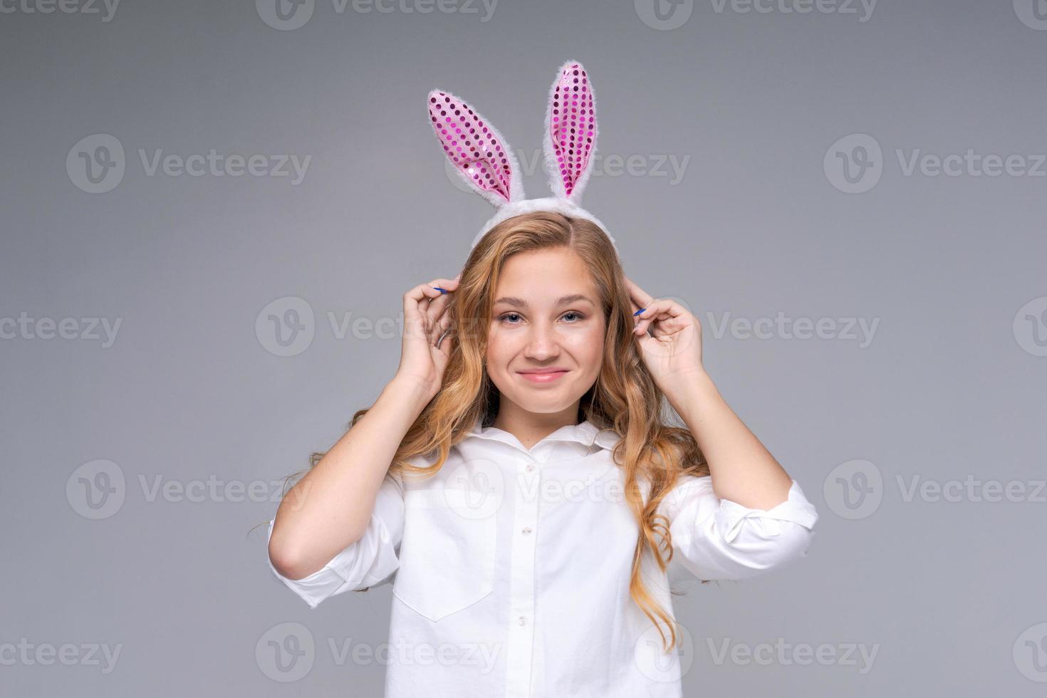 linda chica hermosa con lindas orejas rosas de conejo de pascua, con impaciencia foto