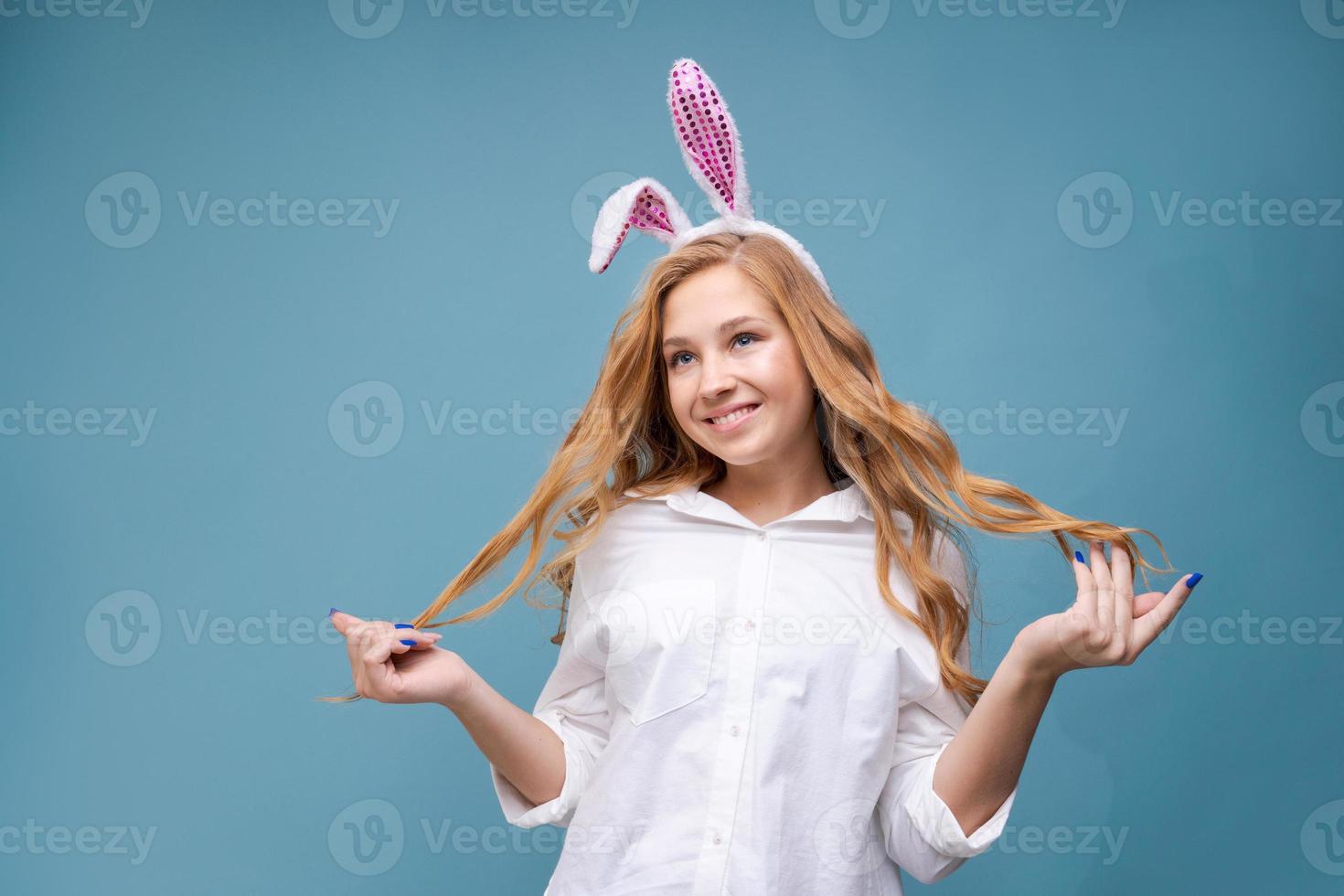 Young beautiful woman in cute easter bunny ears makes a normal gesture, plays photo