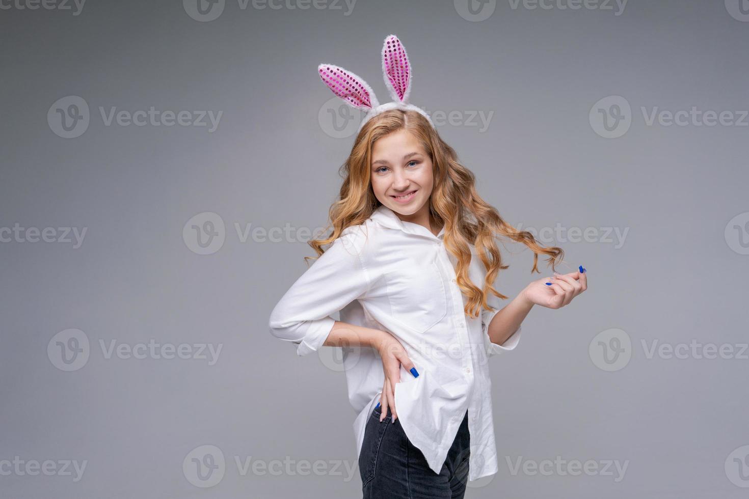 Young beautiful woman in cute easter bunny ears makes a normal gesture, plays photo