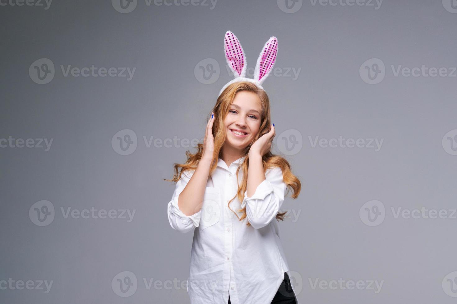 Young beautiful woman in cute easter bunny ears makes a normal gesture, plays photo