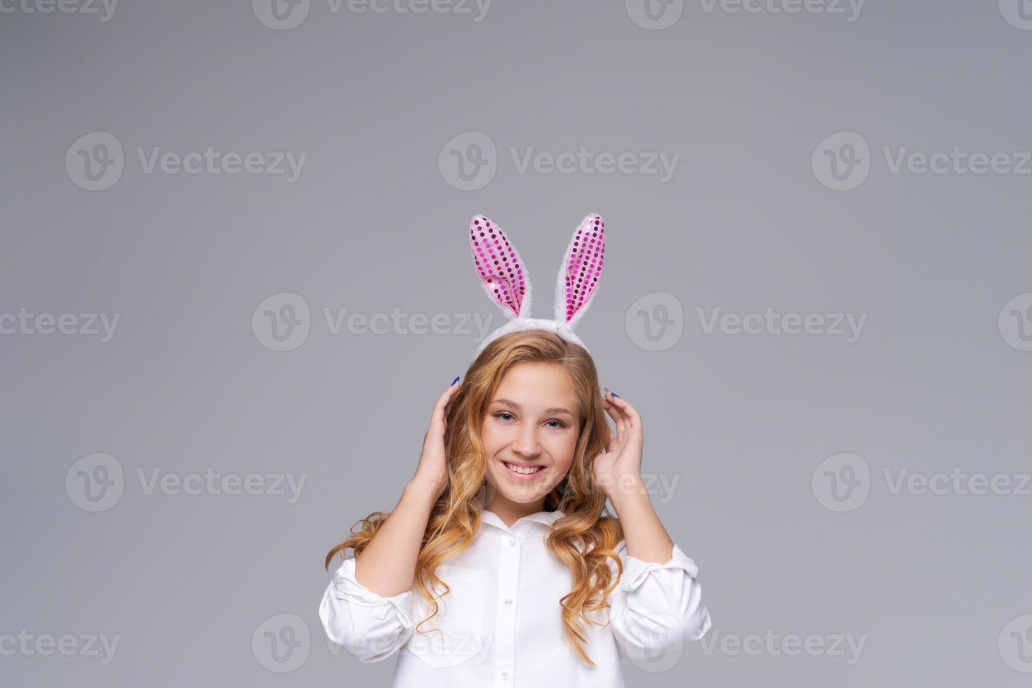 Girl in rabbit ears on her head against backdrop studio. Cheerful suffering photo