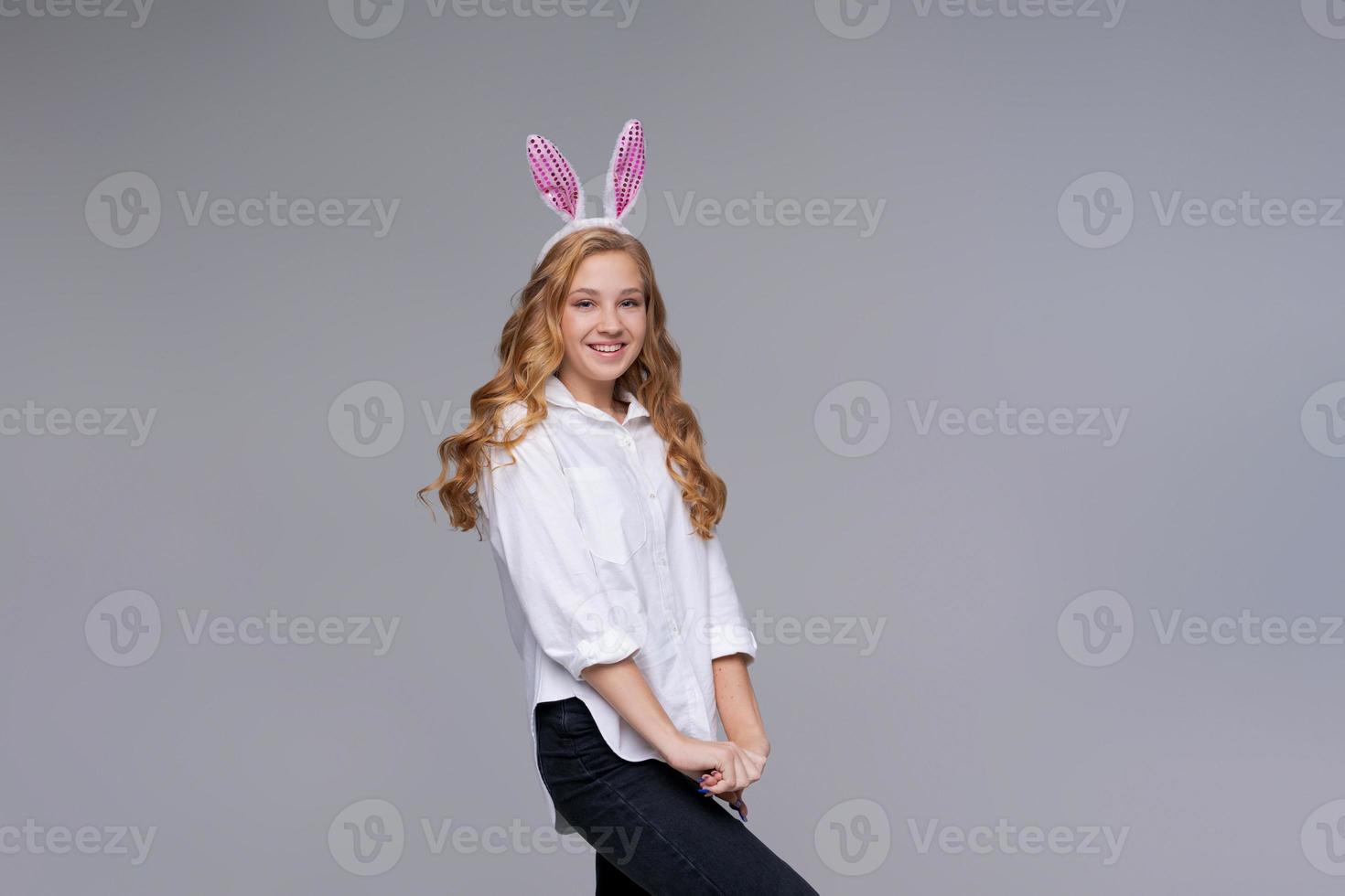 Girl in rabbit ears on her head against backdrop studio. Cheerful suffering photo