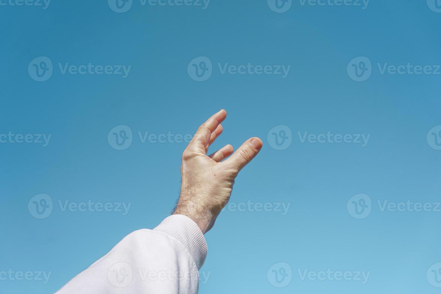 hand up in the air gesturing in the blue sky, blue background photo