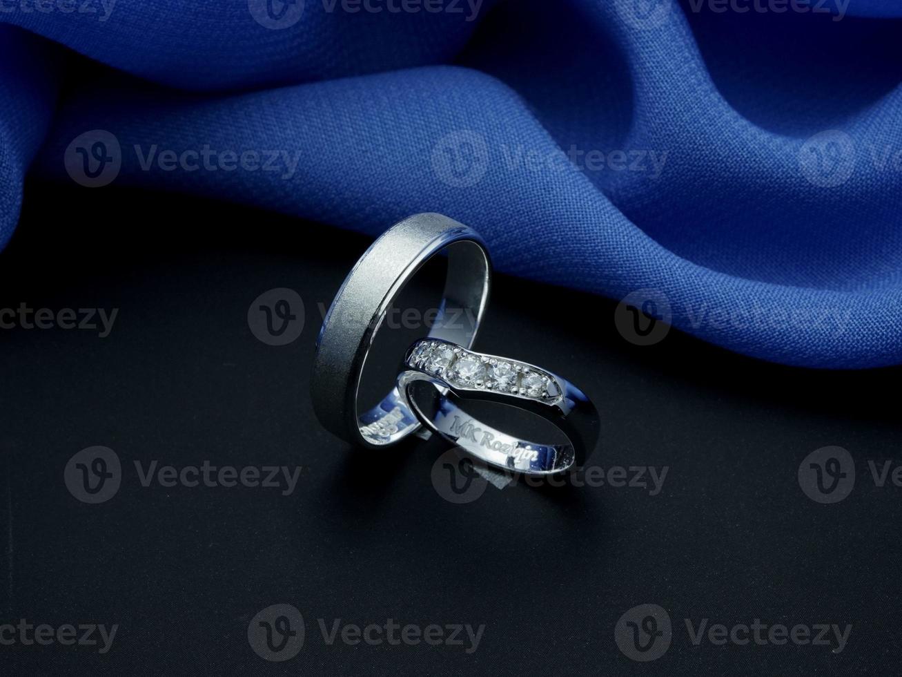 anillo de bodas de oro blanco. anillo de pareja con acabado brillante y apagado con fondo azul y negro foto