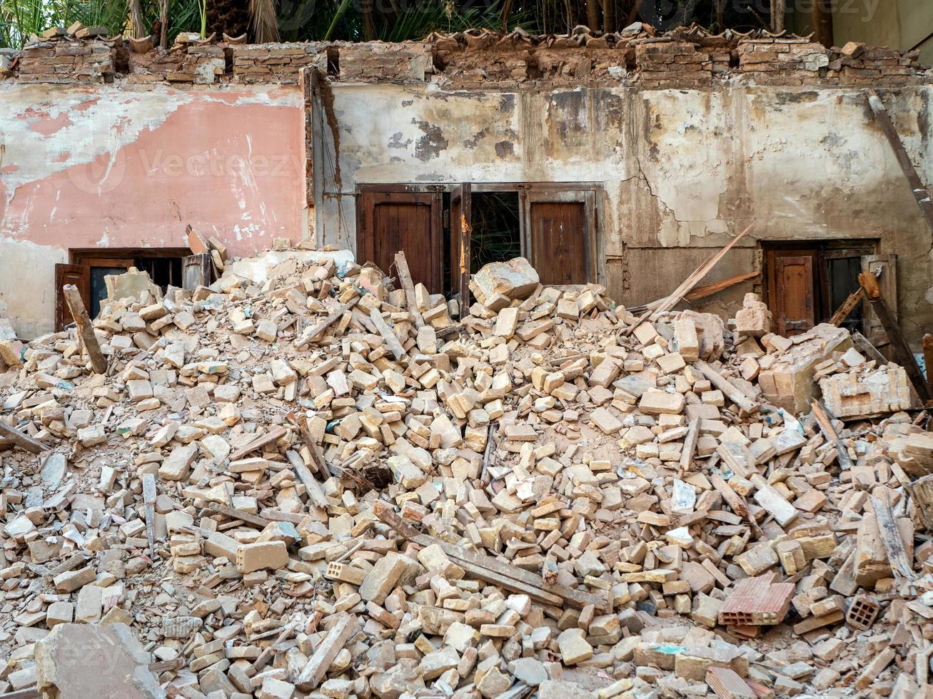 The remains of the demolished building are a pile of bricks and a wall with a door. photo