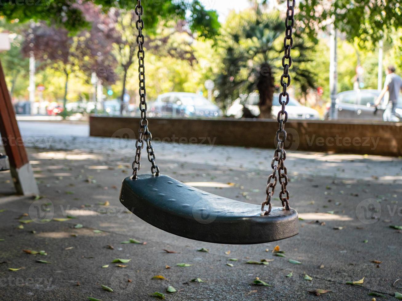 Photo of an empty swing seat hanging on chains on the playground