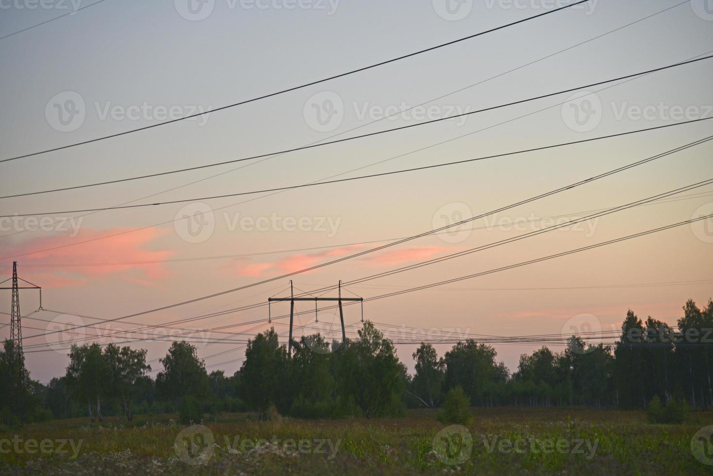 Beautiful high-voltage iron transmission line in the evening in the sunset sky. Landscape evening and wires and power lines. photo