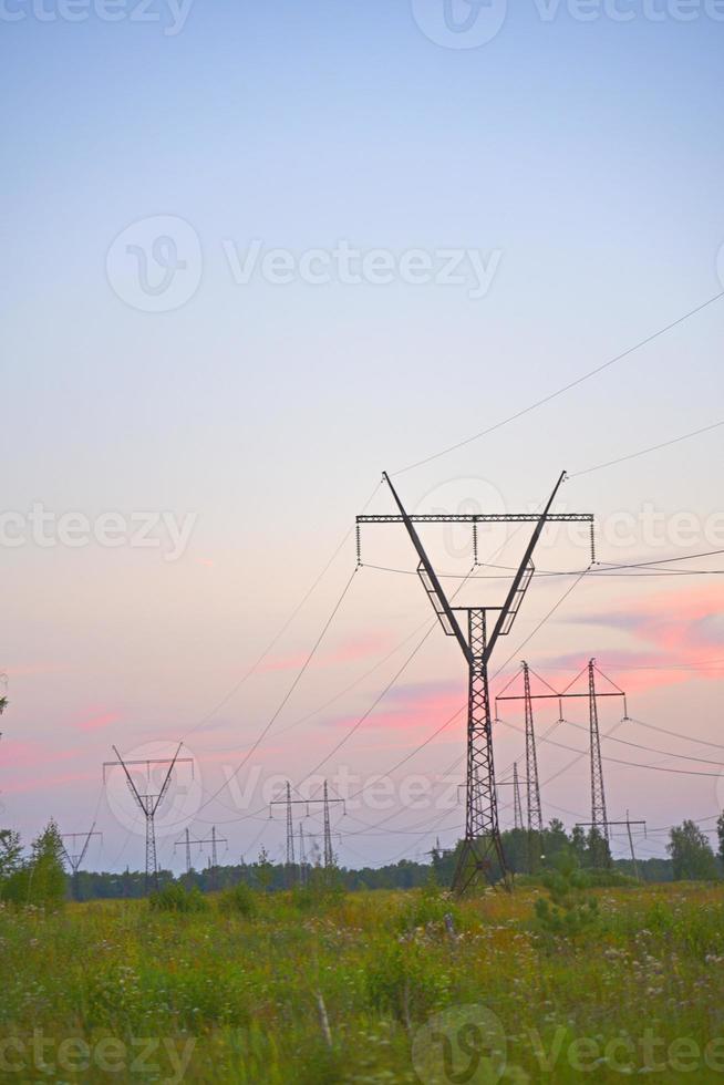 hermosa línea de transmisión de hierro de alto voltaje por la noche en el cielo del atardecer. noche de paisaje y cables y líneas eléctricas. foto