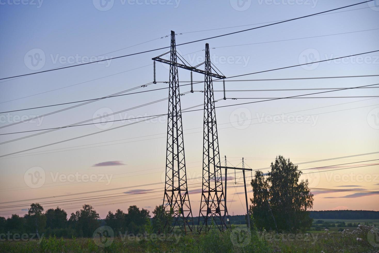 hermosa línea de transmisión de hierro de alto voltaje por la noche en el cielo del atardecer. noche de paisaje y cables y líneas eléctricas. foto