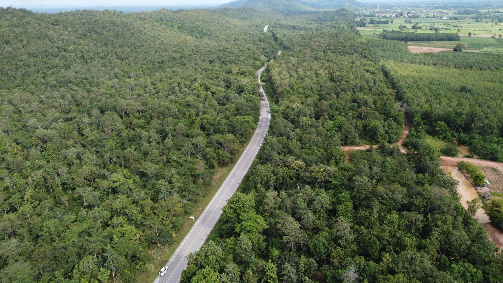 vista aérea de una carretera a través de un bosque al atardecer foto