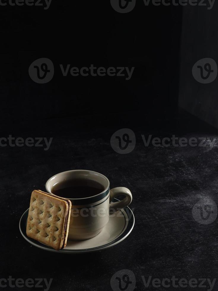 Black coffee and biscuits on the black background photo