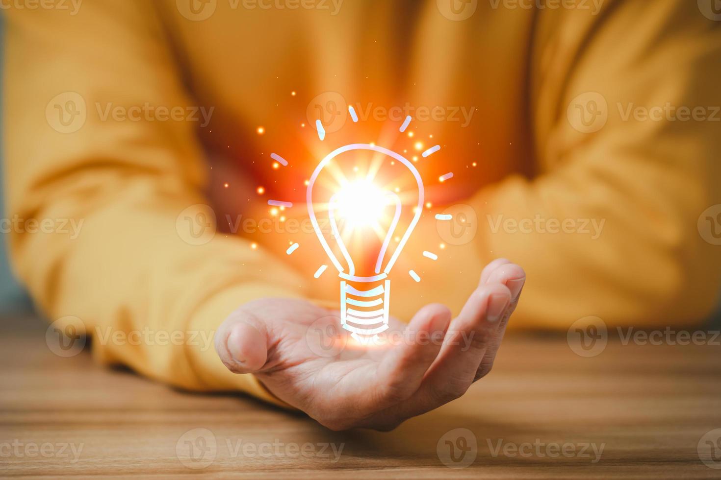 hombre sosteniendo una bombilla de luz abstracta brillante sobre una mesa de madera, ideas para resolver problemas de negocios e ideas creativas de marketing inventando y aprendiendo cosas nuevas. foto