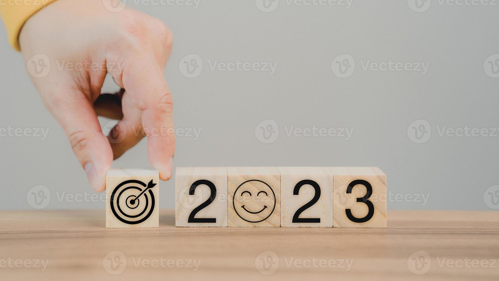 Hand putting wooden cube block with goal icon and 2023 icon on table background. Start new year 2023 with goal plan for work, action plan, strategy, new year business vision. photo