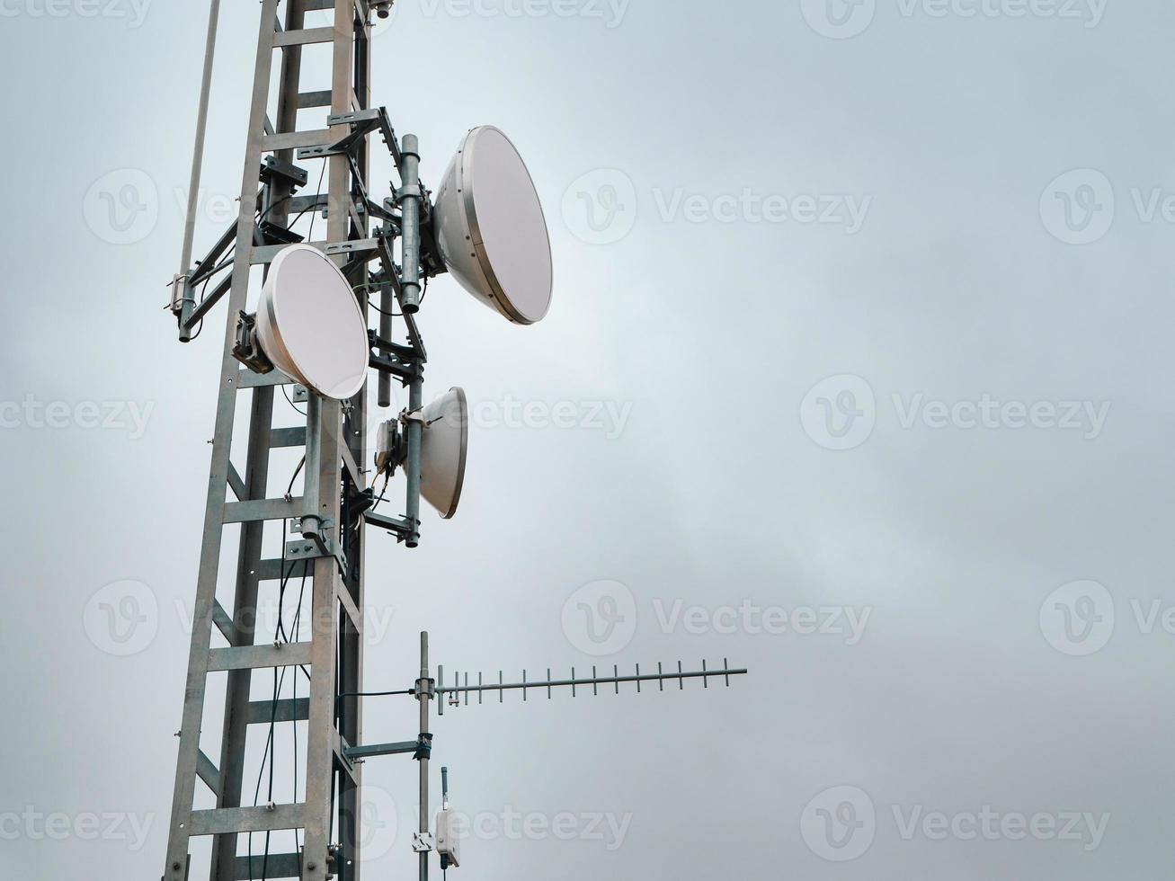 antenas celulares en una torre de metal contra un cielo gris foto