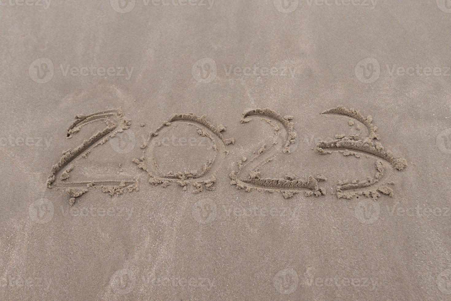 text 2023 on the sand of beach symbol new year 2023 photo