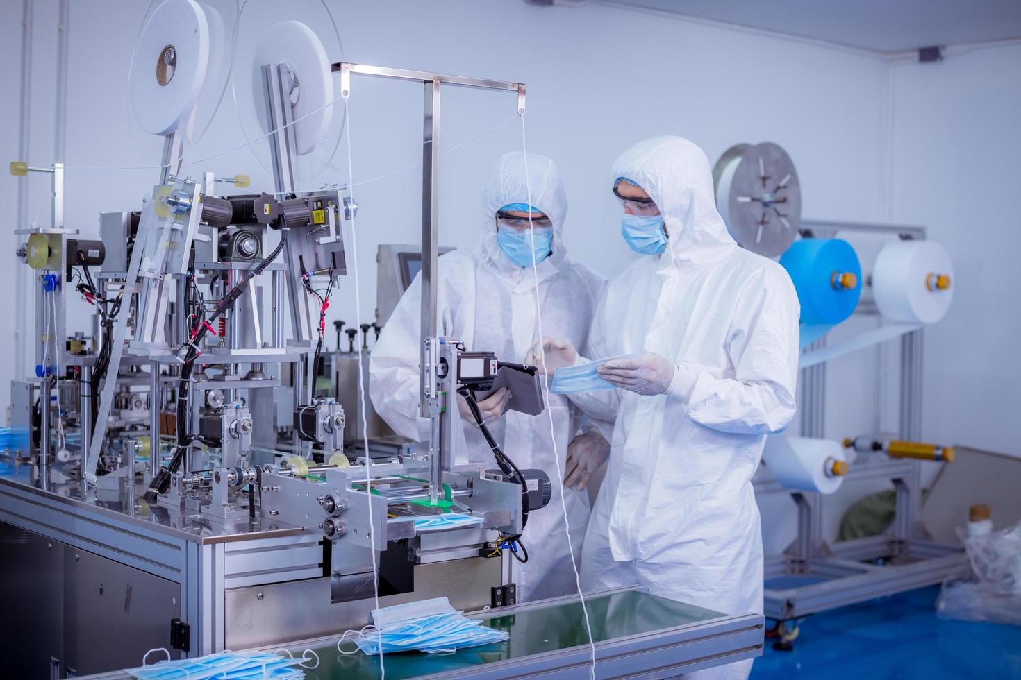 Technician worker wearing protective suite , glove are inspect ion with check  face mask manufacturing process to safe and against from virus. photo