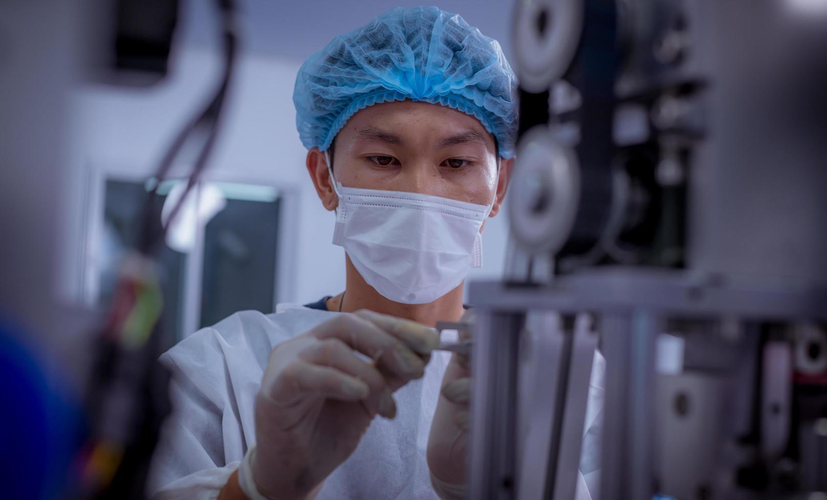 Technician worker wearing protective suite , glove are inspect ion with check  face mask manufacturing process to safe and against from virus. photo