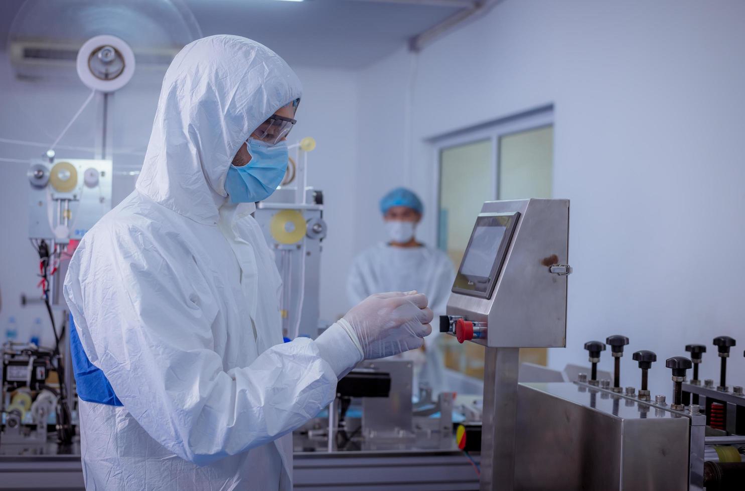 Technician worker wearing protective suite , glove are inspect ion with check  face mask manufacturing process to safe and against from virus. photo