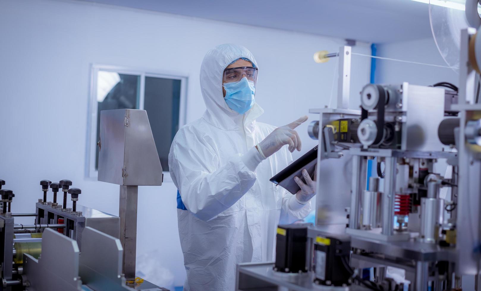 Technician worker wearing protective suite , glove are inspect ion with check  face mask manufacturing process to safe and against from virus. photo