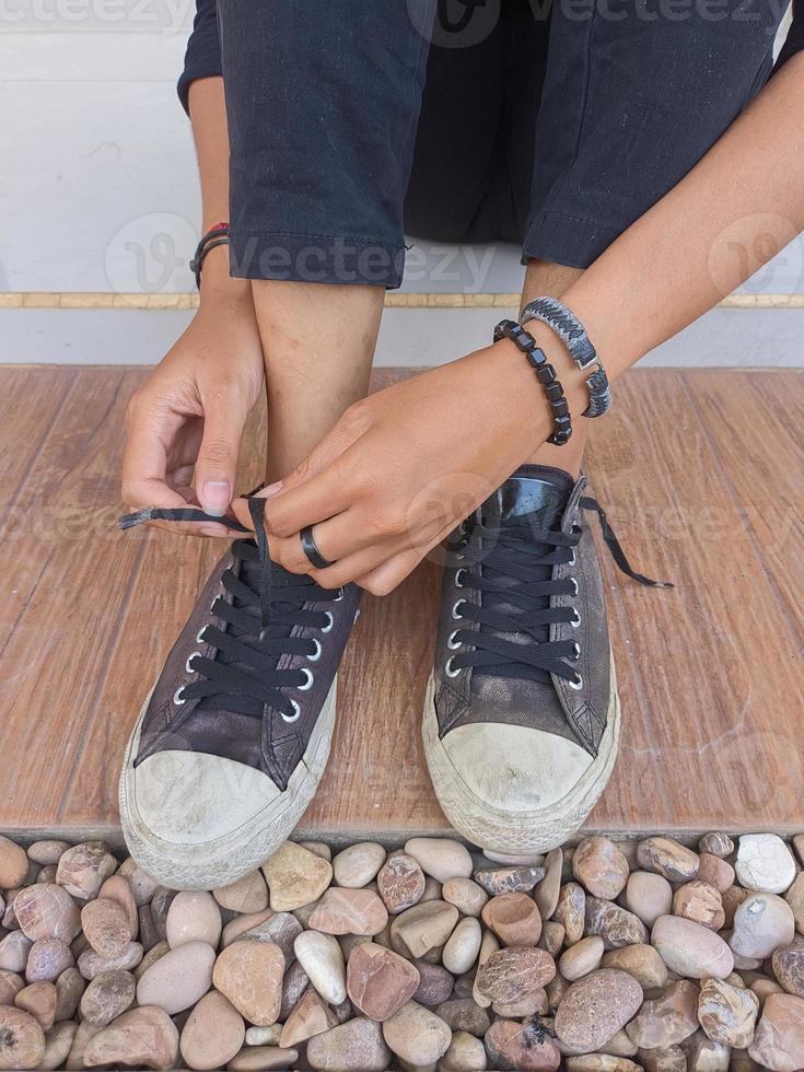 retrato de pie de una mujer joven que usa y ata cordones de zapatos en el porche de la casa foto