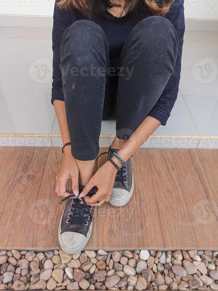 foot portrait of a young woman wearing and tying shoelaces on the porch of the house photo