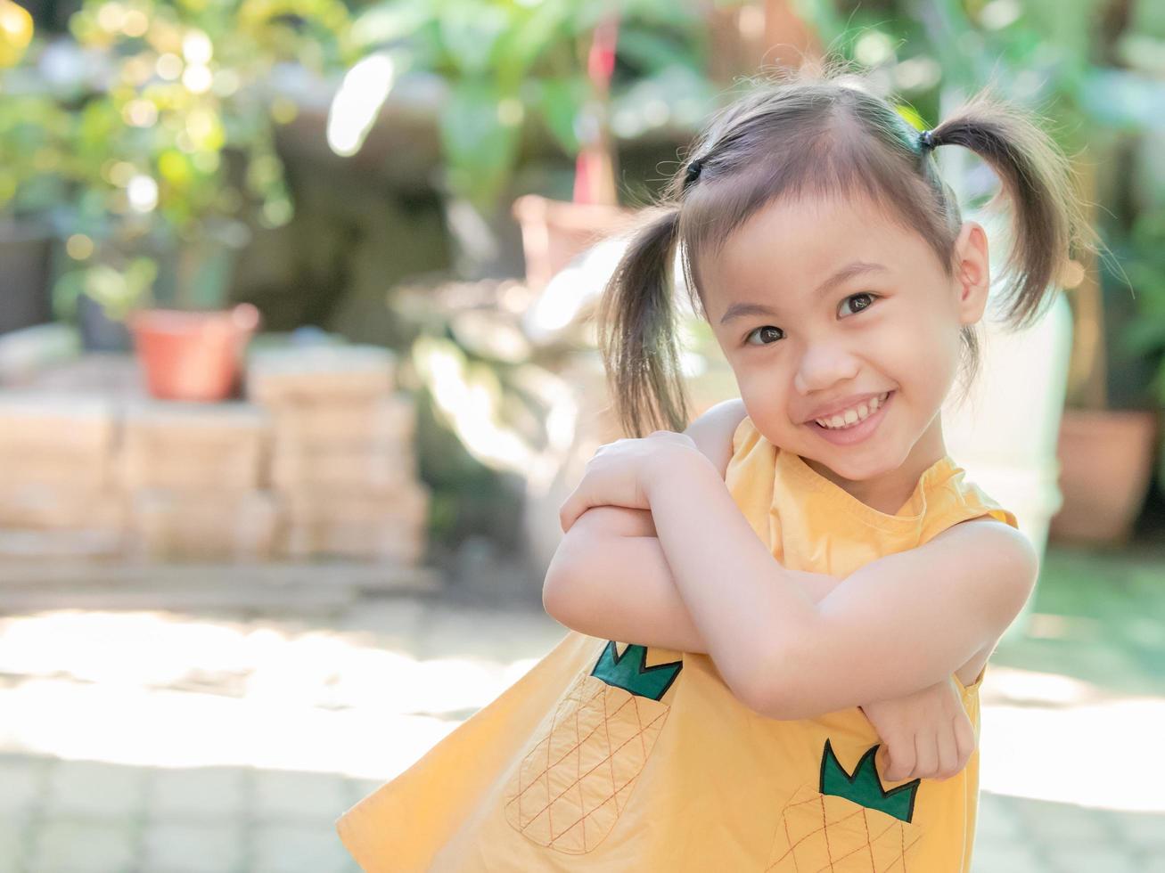 positiva encantadora niña asiática de 4 años de edad, pequeña niña preescolar con adorable cabello de coletas sonriendo mirando a la cámara. foto