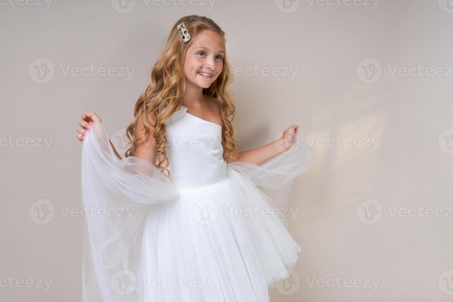 Photo an adorable cute schoolgirl angel in white dress, on a light background.