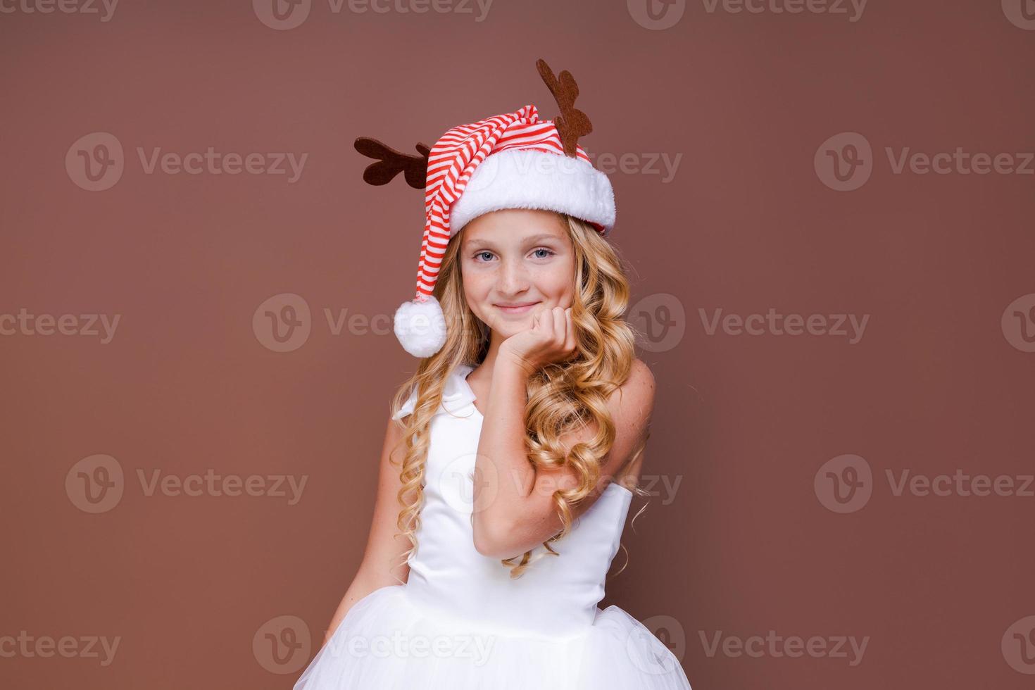 Happy funny child girl in red christmas deer costume smiling looking at camera. photo