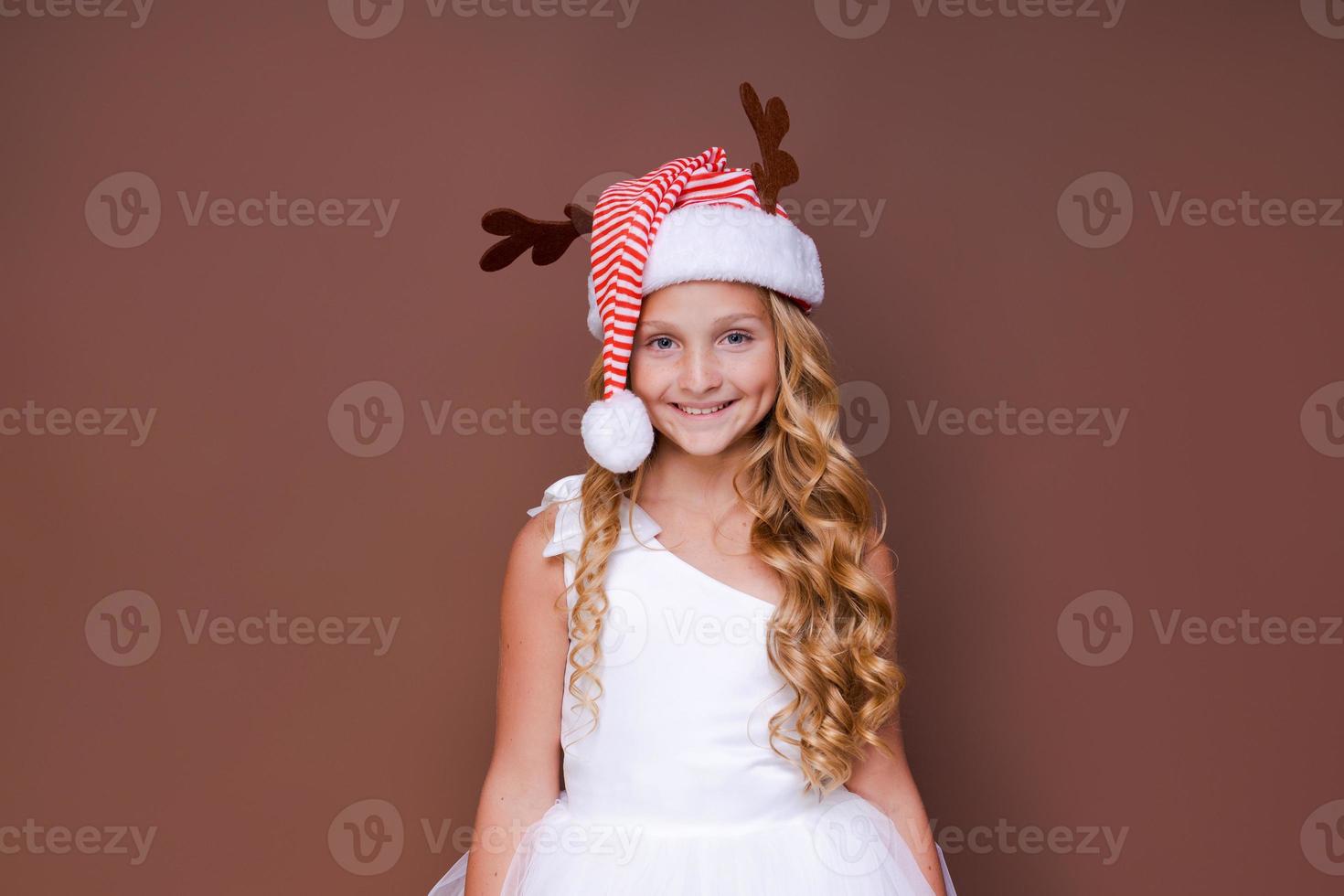 Happy funny child girl in red christmas deer costume smiling looking at camera. photo