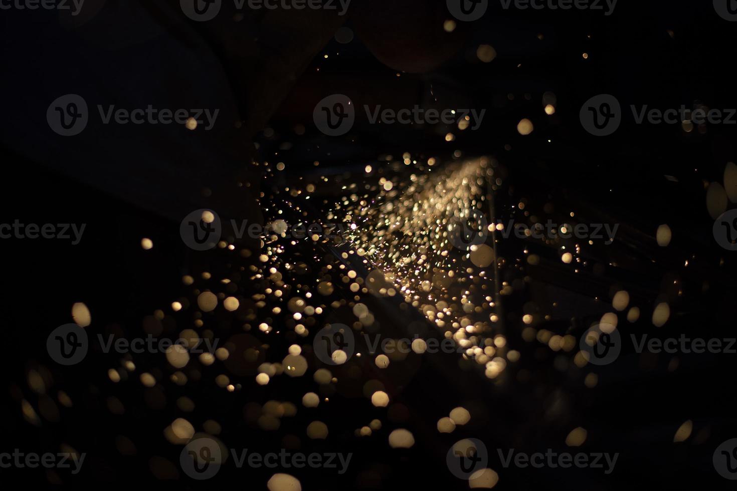 Sparks in dark. Stream of lights on black background. Metal crushing. High temperature. photo