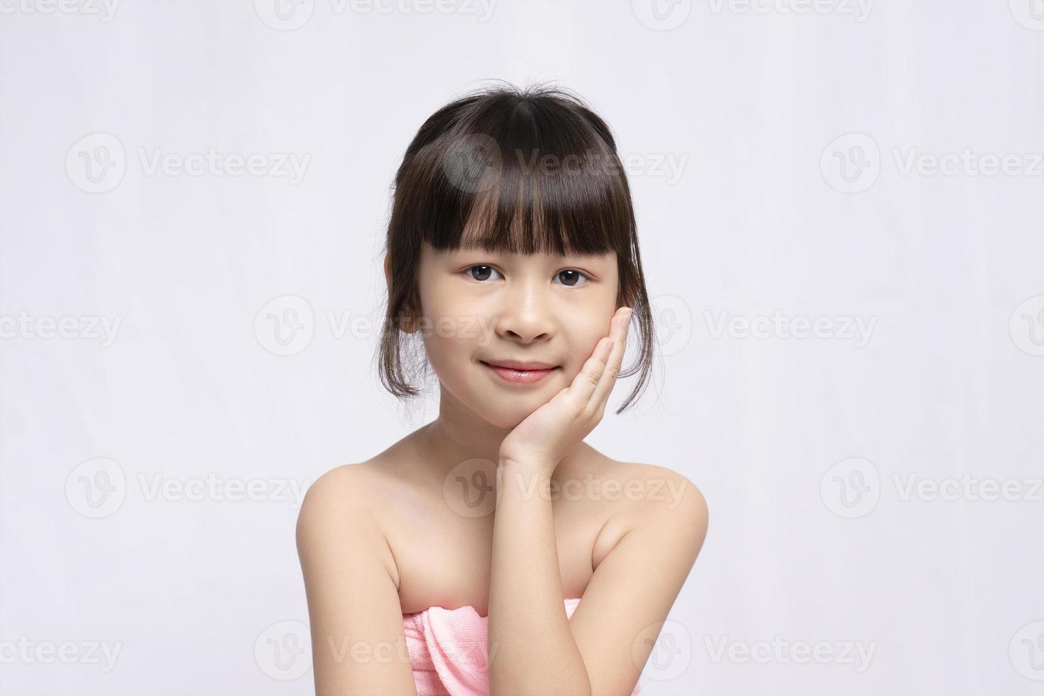 Asian young girl bright face and put his hand to his face on white background, Skin care beauty treatments concept. White model with clean, health skin of face. Children's products photo