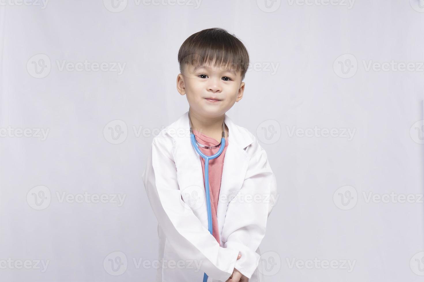 boy wearing a doctor's suit with a medical stethoscope on a white background. Preschool children pretend to be a pediatrician. Childhood dream of becoming a doctor photo