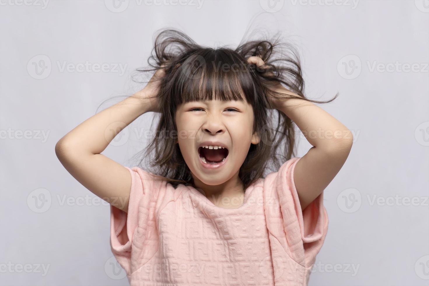 Angry Asian girl on white background, angry child, frantic gesture expression and put his hand on his head. photo