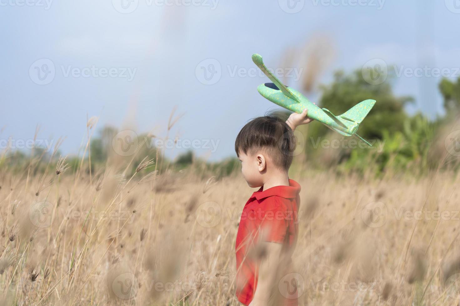 boy happy playing with toy plane in nature and clear morning sky, Child concept and dream plane to become pilot. want to fly like an airplane photo