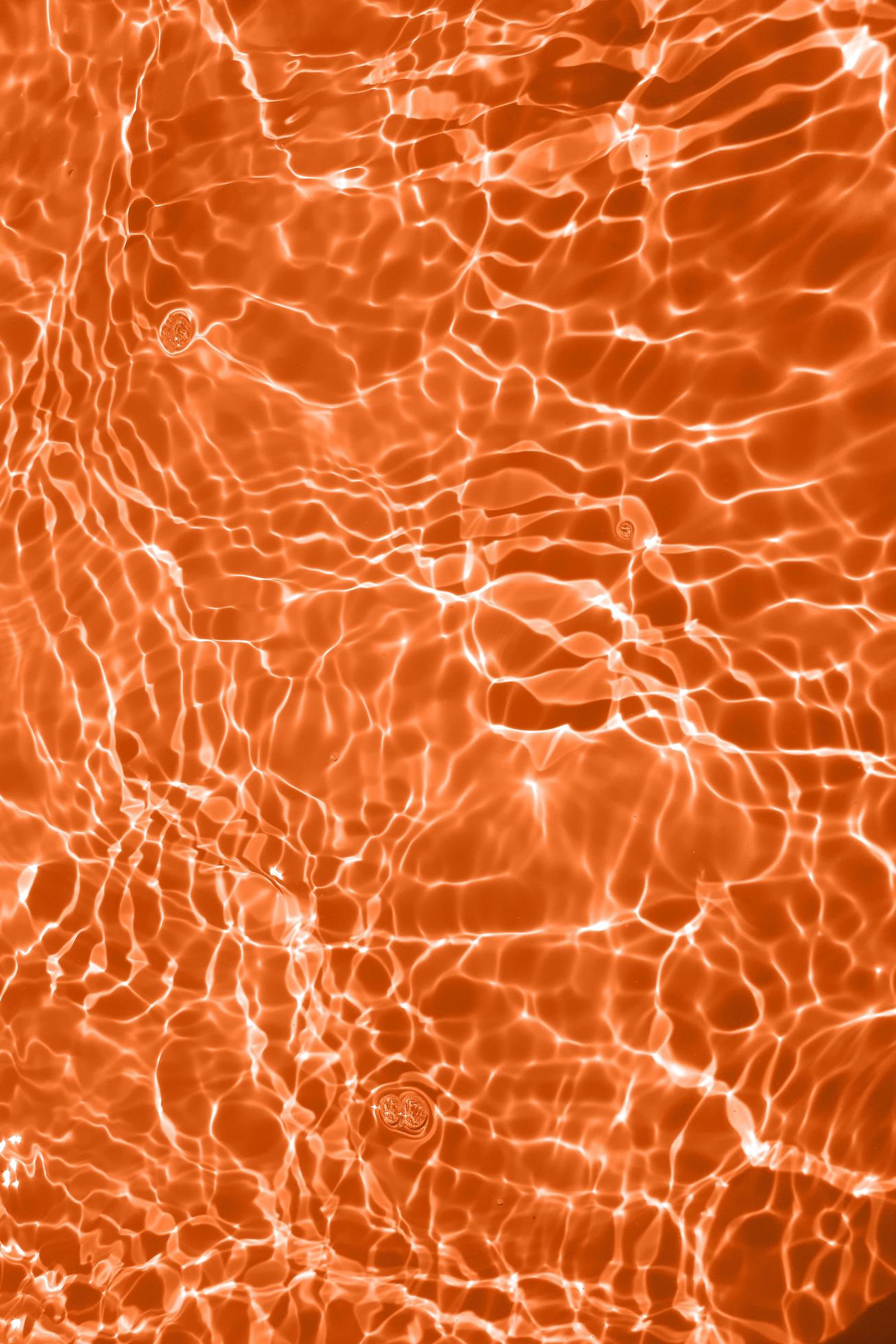 Defocus blurred transparent orange colored clear calm water surface