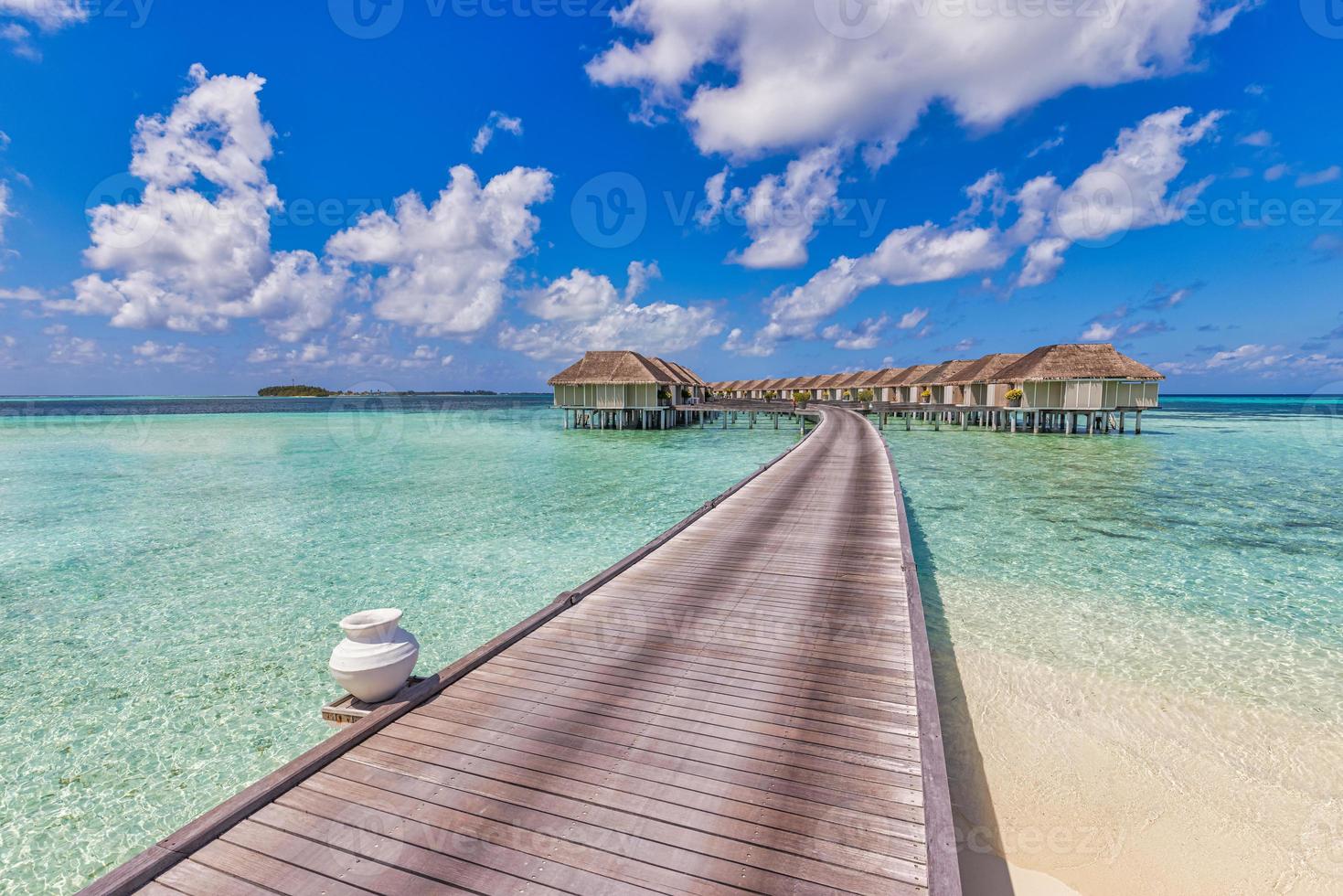 isla soleada de maldivas, resort de lujosas villas de agua y muelle de madera. hermoso cielo y nubes y fondo de playa para vacaciones de verano y concepto de viaje. increíble vista panorámica de la playa, turismo foto