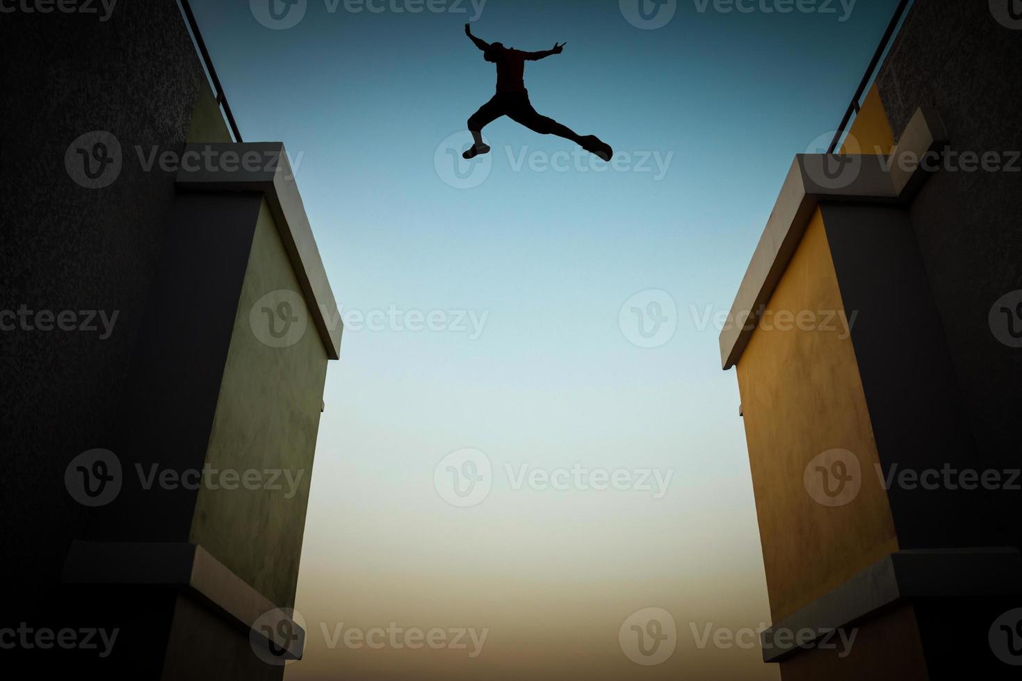 concepto de saltar obstáculos, la silueta de un hombre saltando entre dos edificios altos. foto