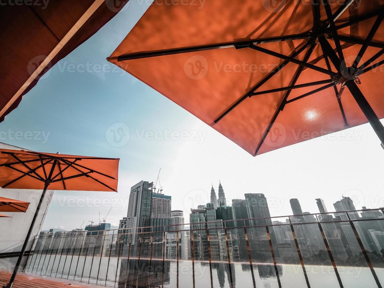 Roof top pool with red umbrellas ovelooking the city skyline photo