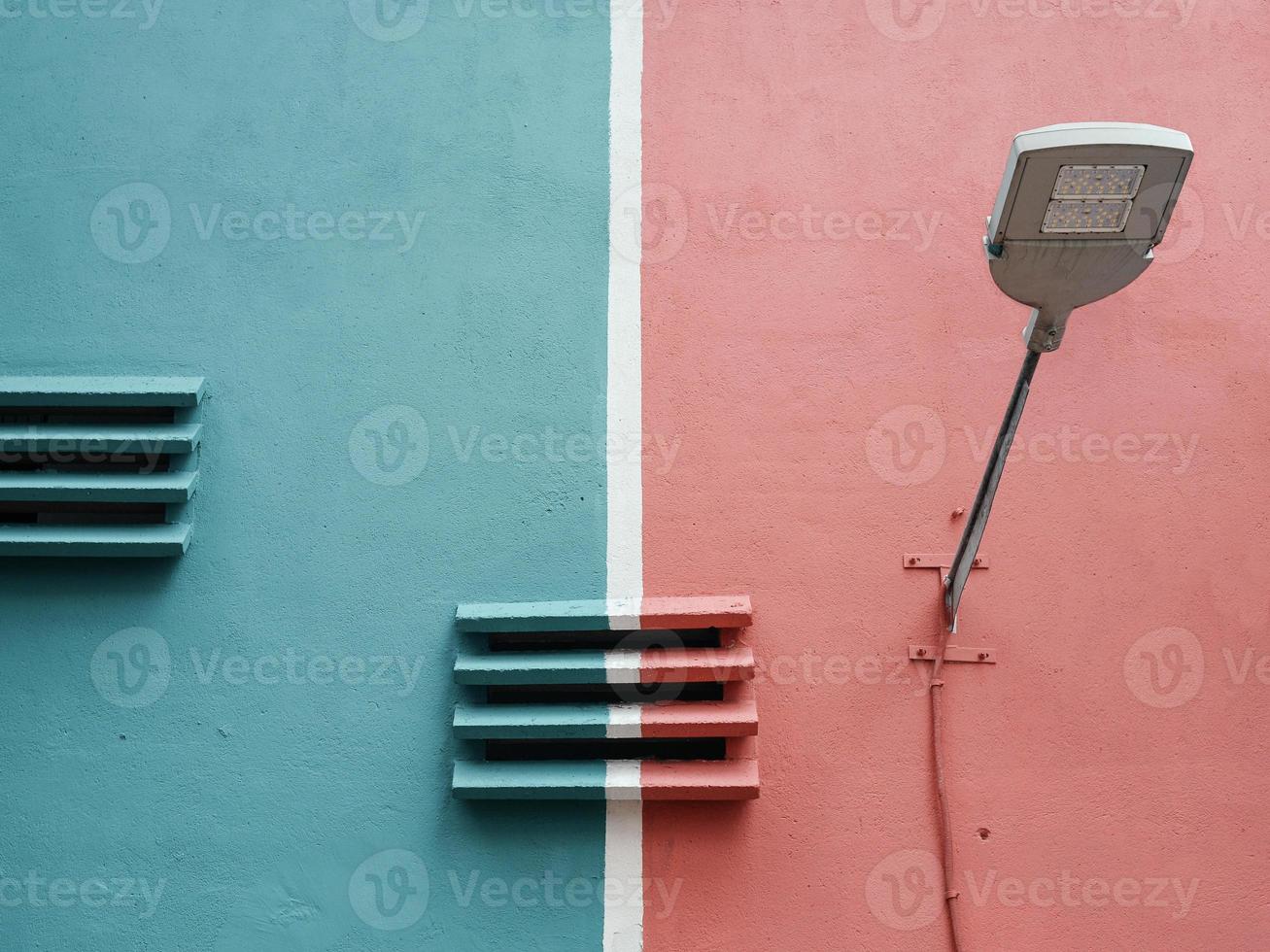 Street lamp and concrete ventilaion louvres against red and blue wall photo