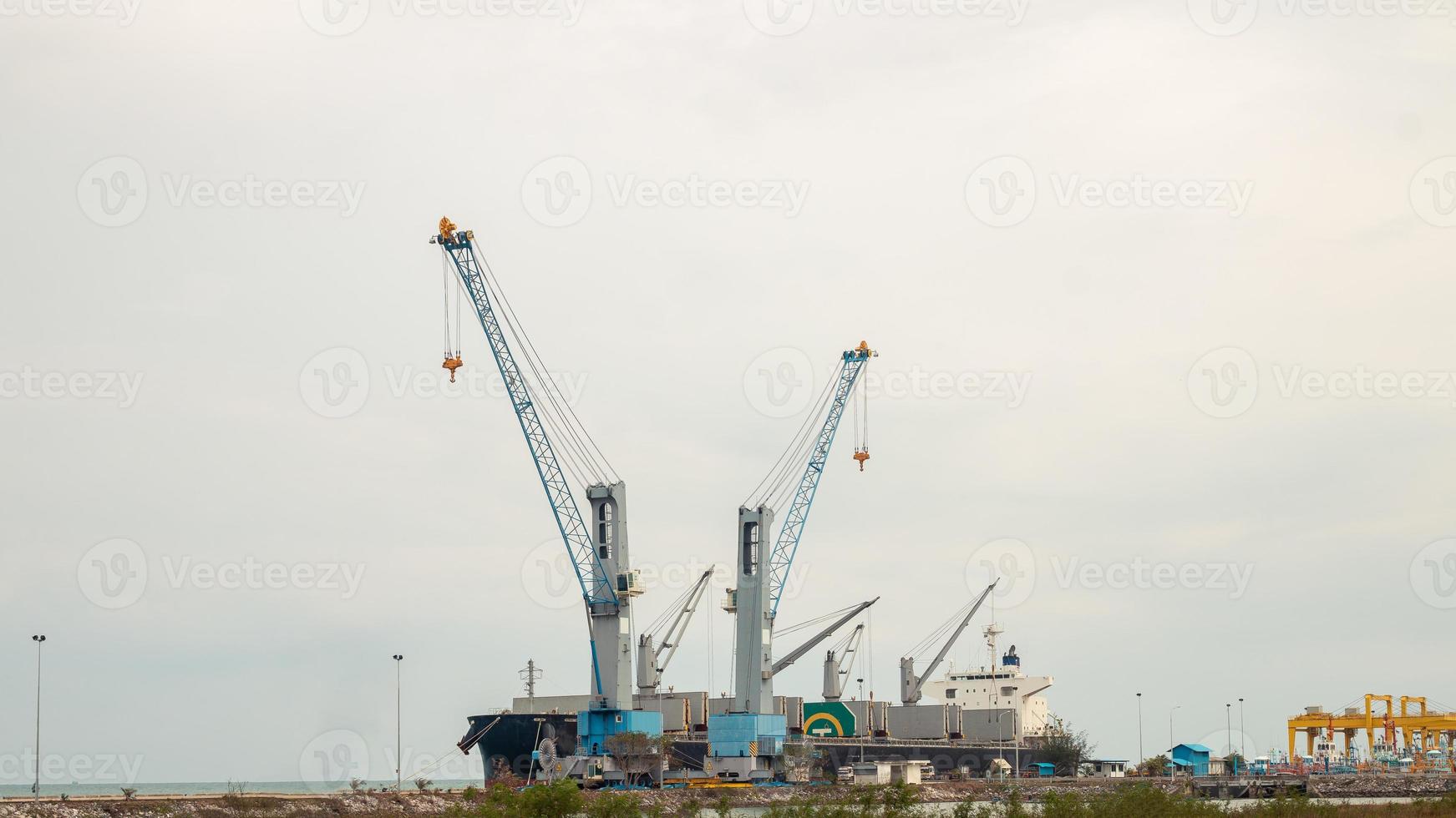 Large cargo cranes and large cargo ships dock at the harbor. photo