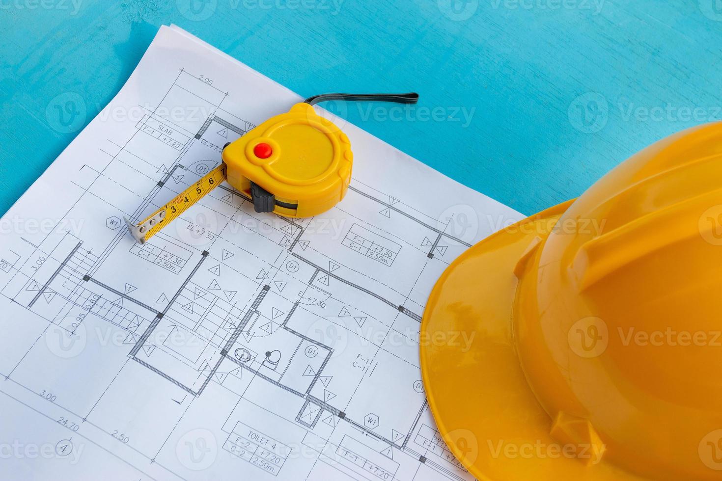 Construction drawings, safety helmets and tape measure on the blue wooden background photo